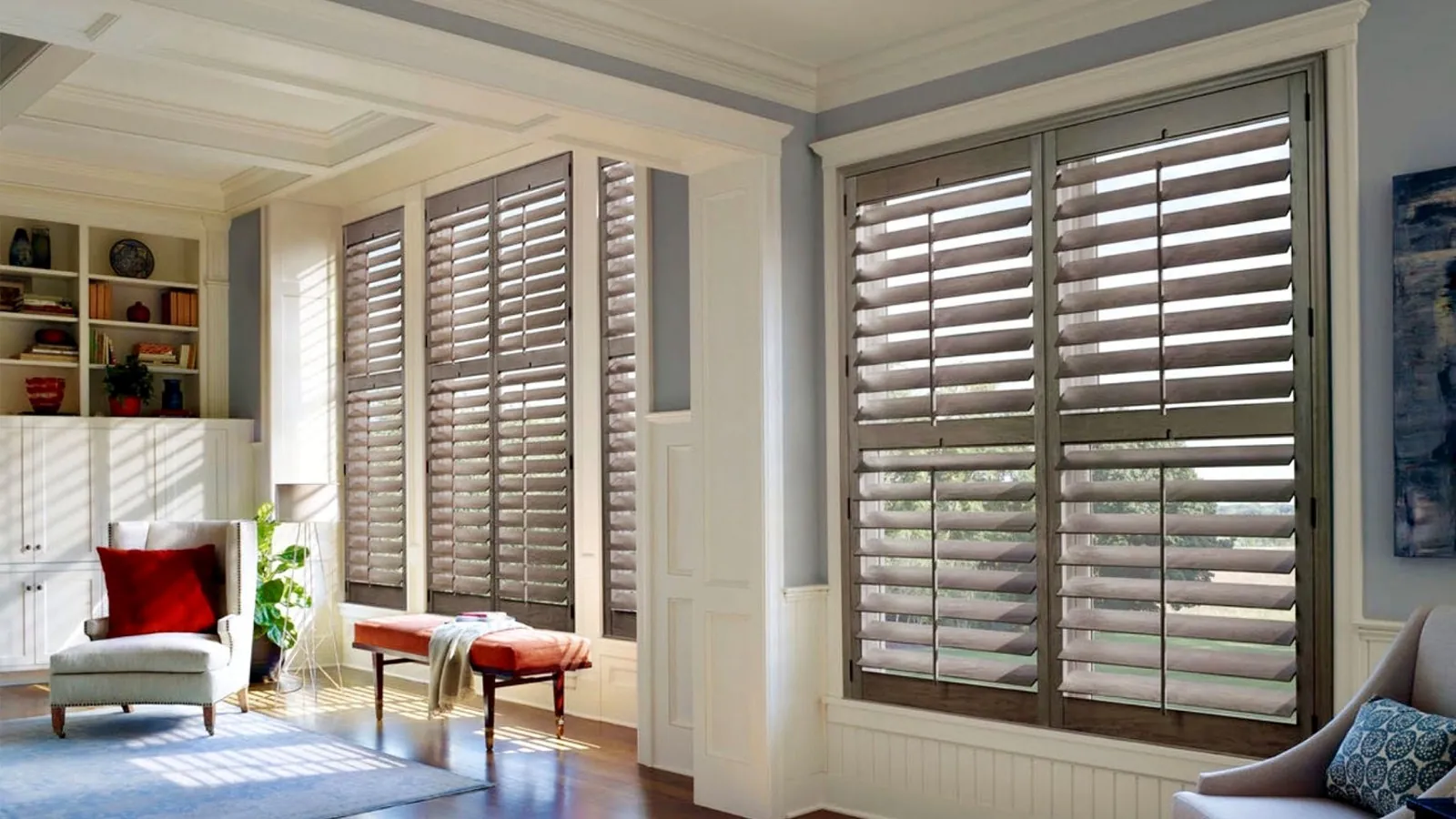 Grey stained wood plantation shutters across a bay window and a tall window in a panelled living room